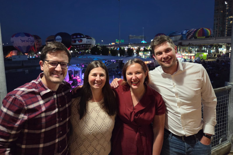 Eye Hero team members posing together at the Louisville event with hot air balloons in the background